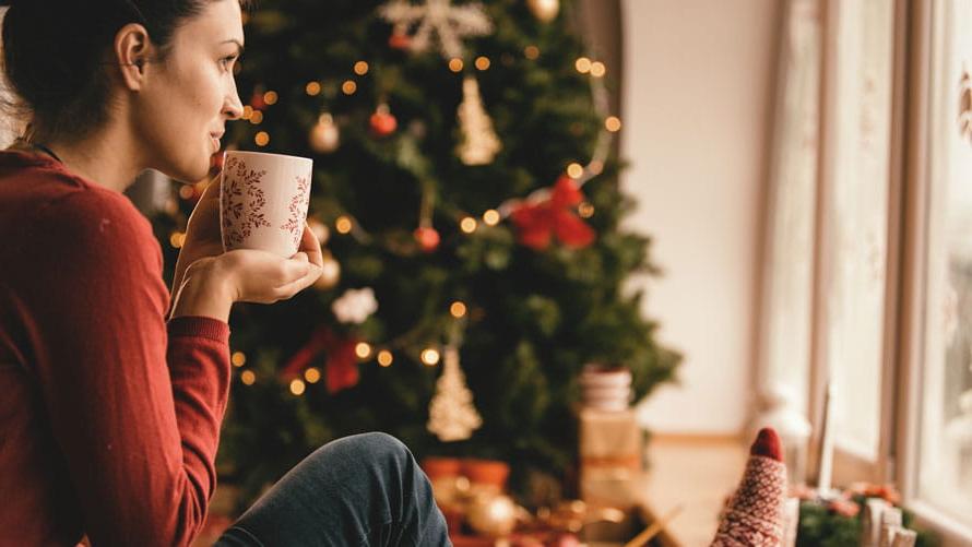 年轻女子在圣诞树旁喝茶.