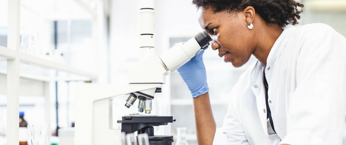 female researcher looking into a microscope