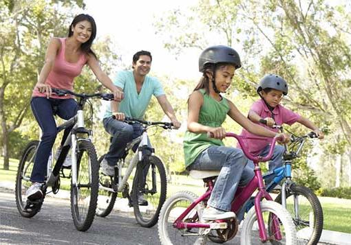 妈妈和爸爸带着年幼的女儿和儿子骑自行车