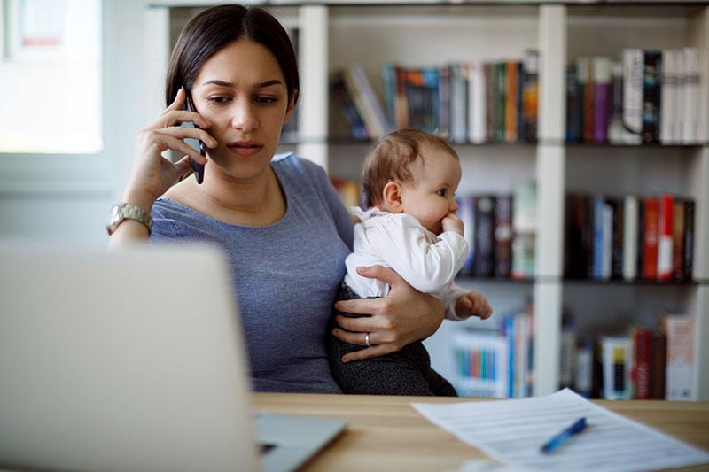 Busy working Mom on cell phone and laptop holding baby